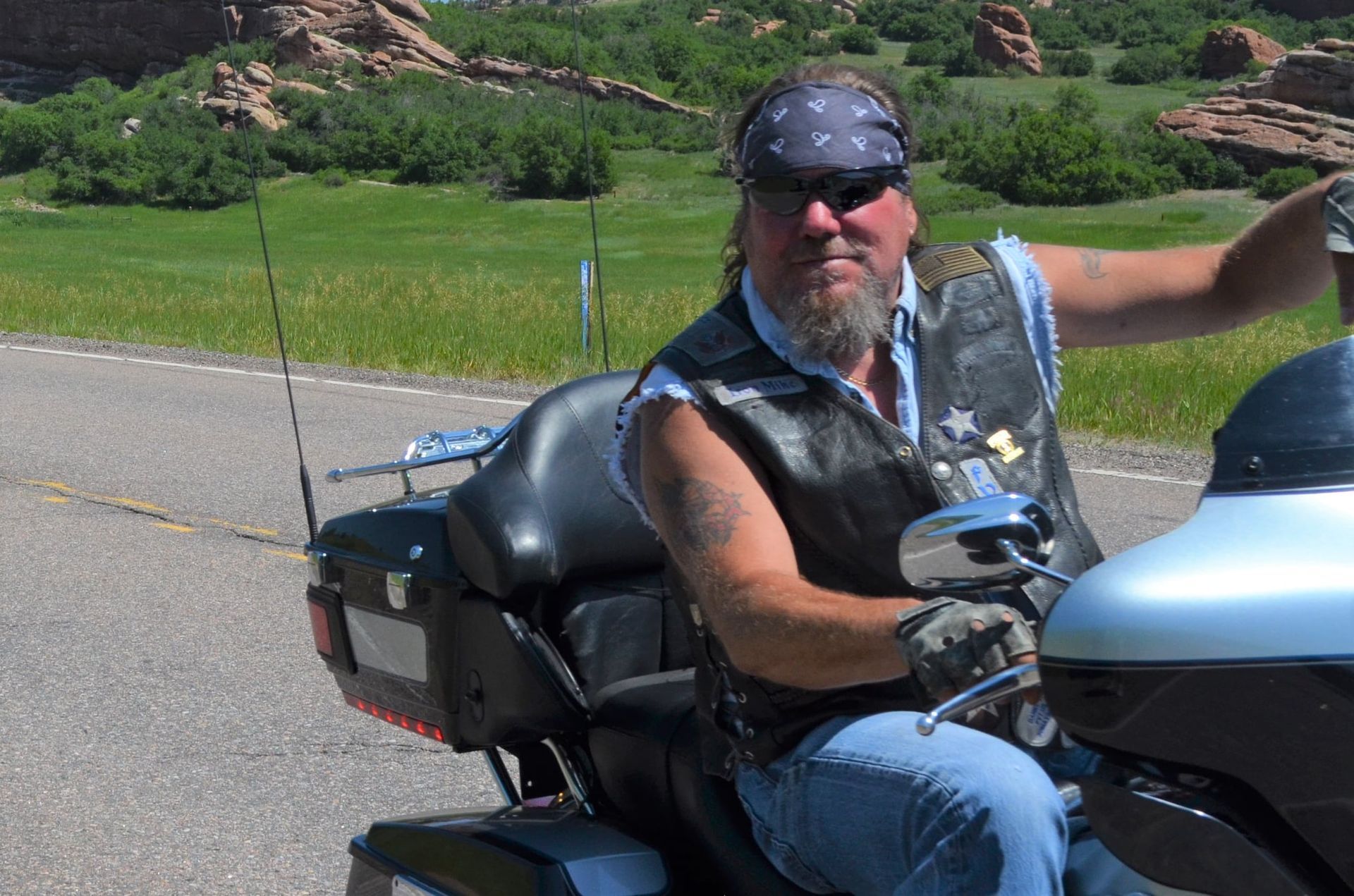 A man wearing sunglasses and a bandana is sitting on a motorcycle