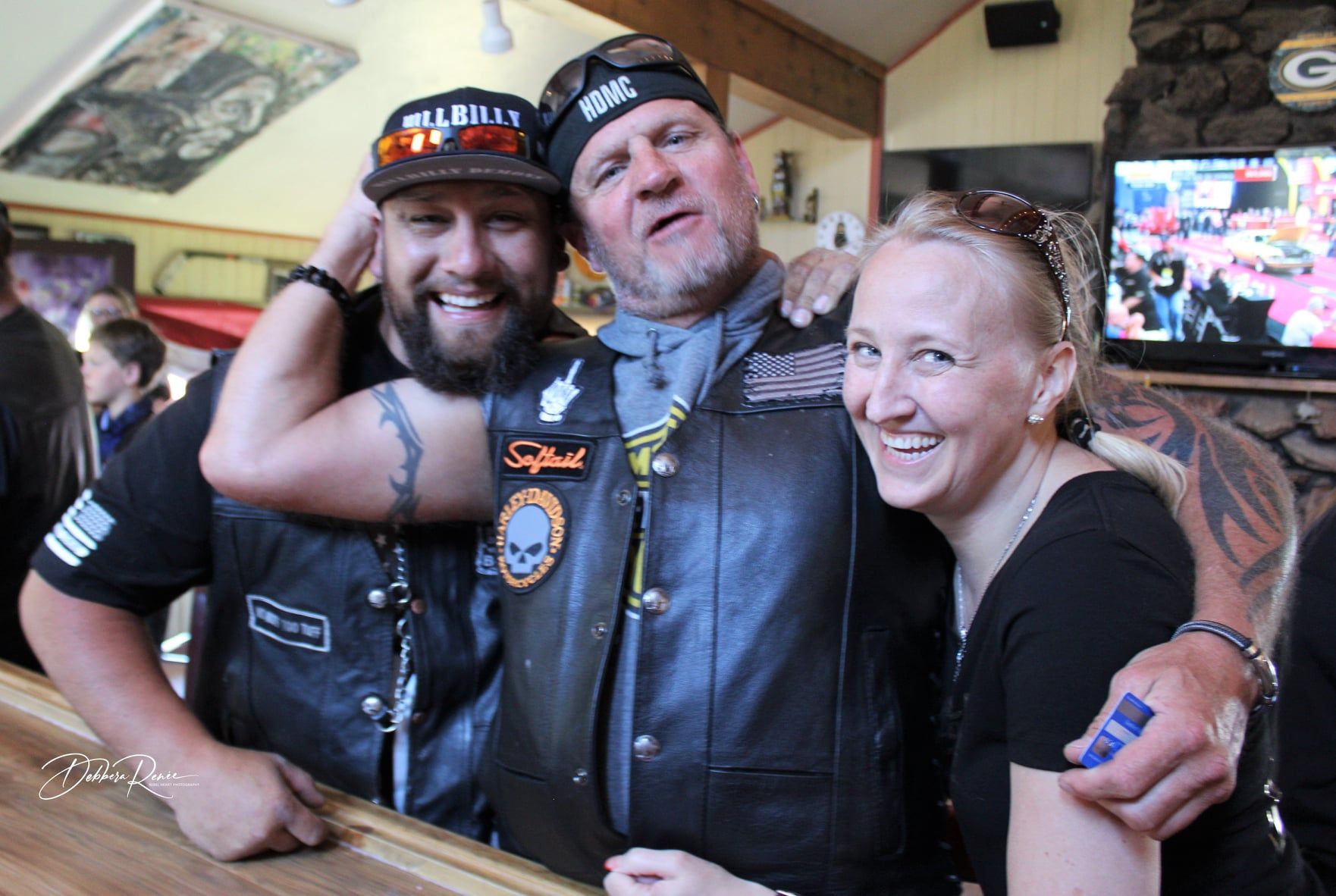 Two men and a woman are posing for a picture in a bar.