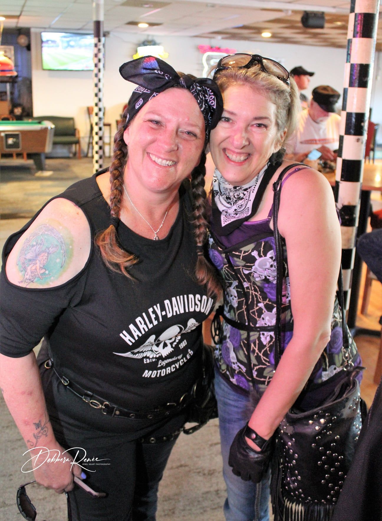 Two women wearing harley davidson shirts are posing for a picture