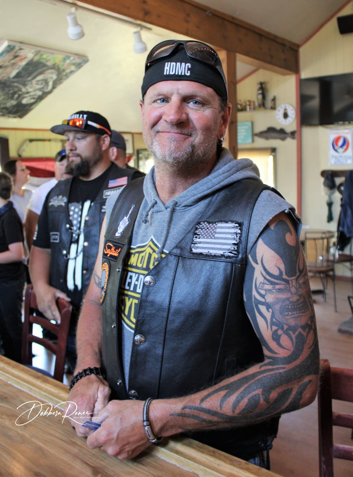 A man wearing a hat that says mvmc is standing at a bar