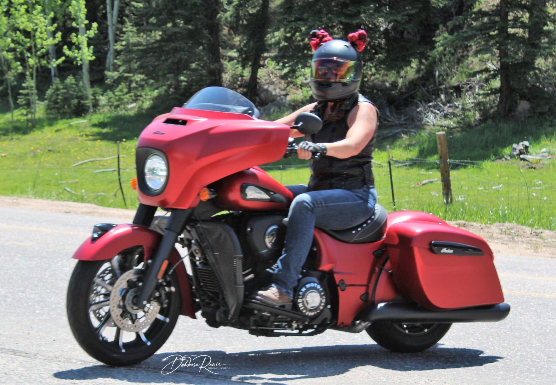 A woman wearing a helmet is riding a red motorcycle