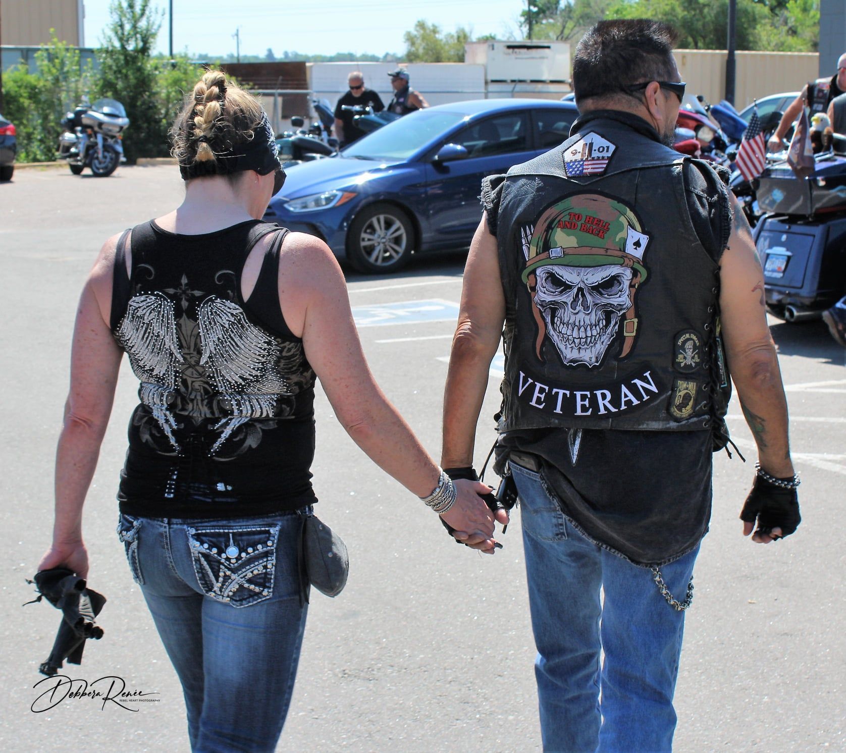 A man wearing a veteran vest holds hands with a woman
