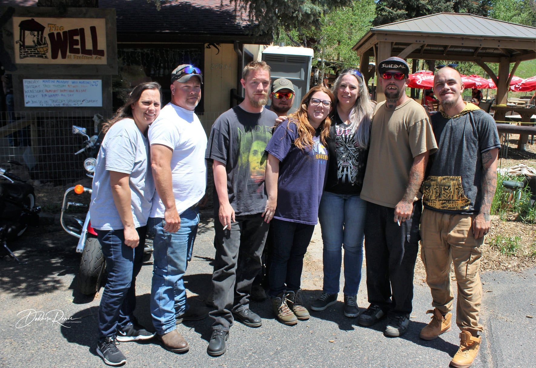 A group of people are posing for a picture in front of a well restaurant.