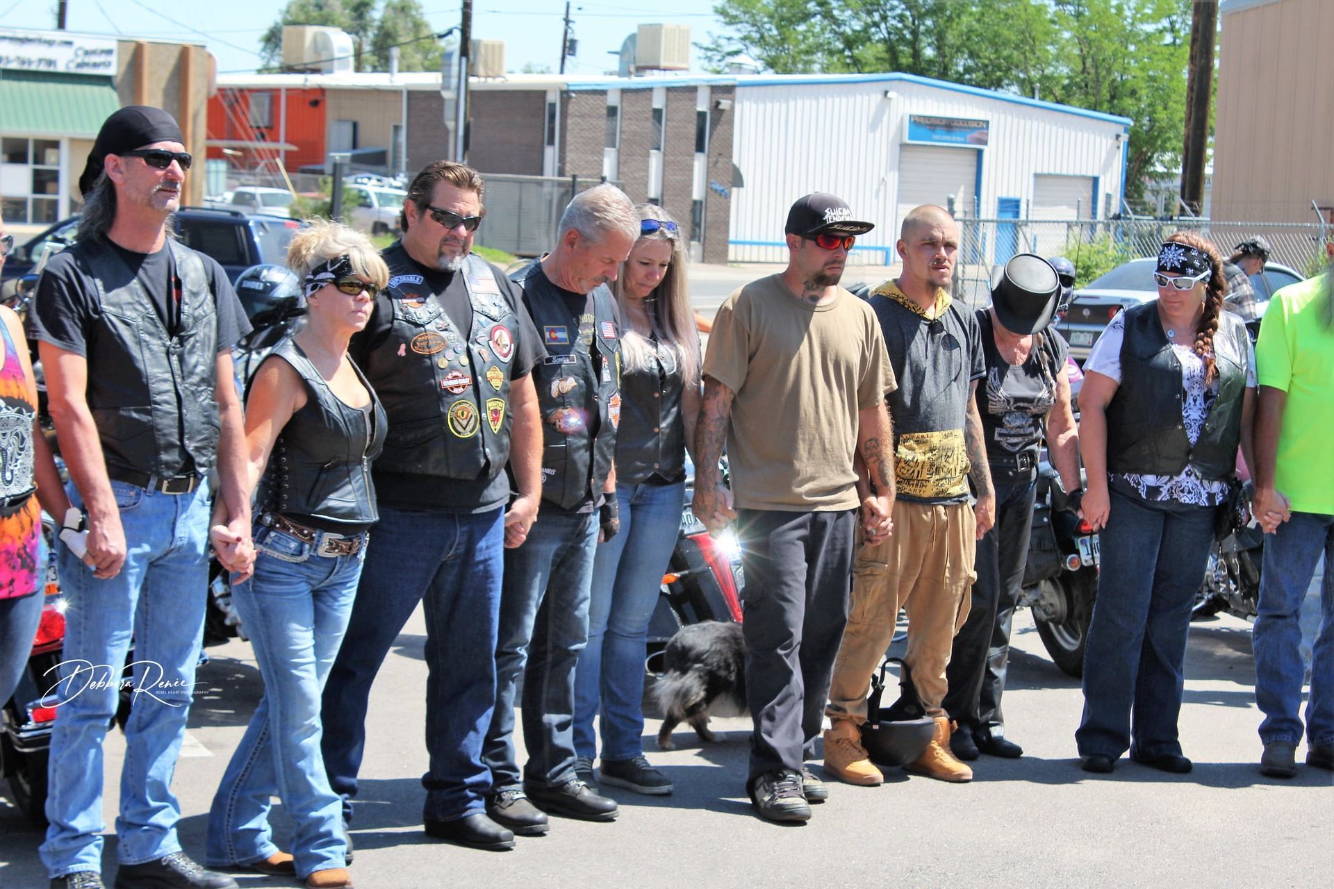 A group of people standing in a line with motorcycles in the background