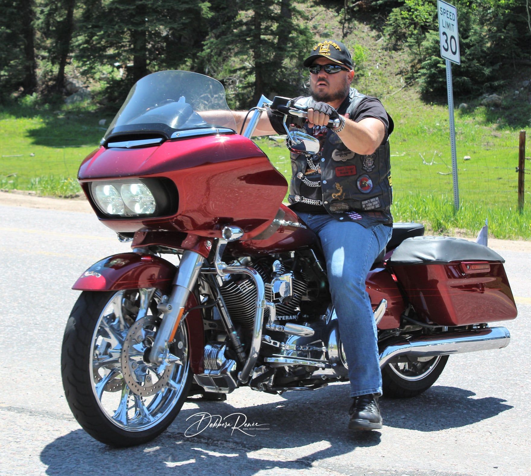 A man is sitting on a red harley davidson motorcycle
