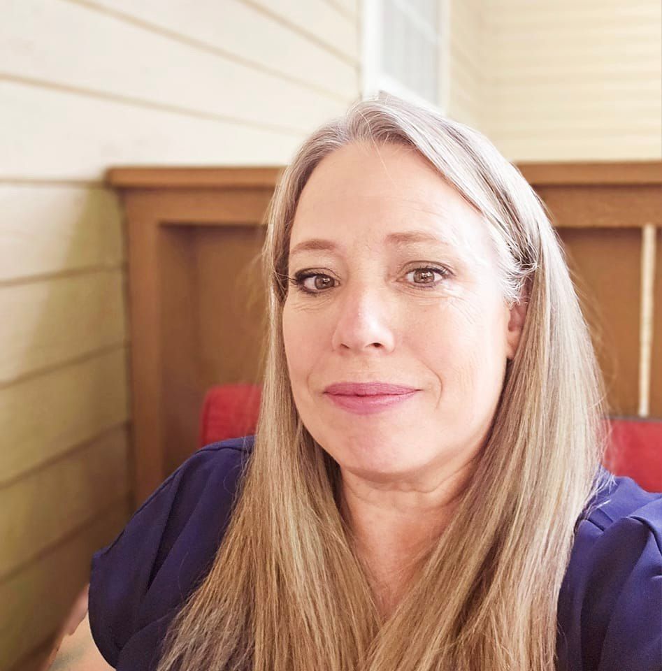 A woman with long blonde hair is smiling for the camera