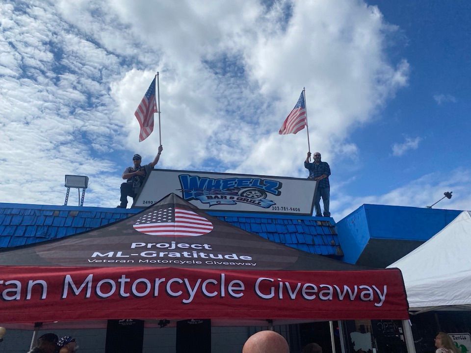 Two men are standing on the roof of a building holding american flags.