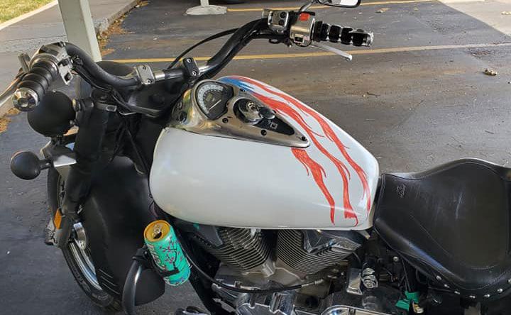 A motorcycle is parked in a parking lot with a can of soda on the seat.