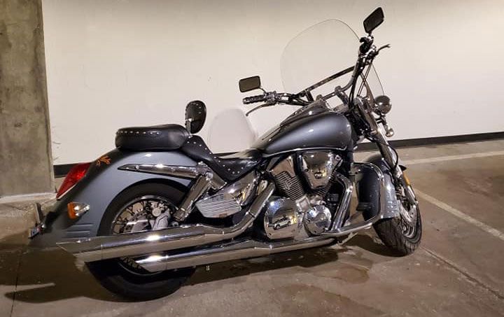 A motorcycle is parked in a parking lot next to a wall.