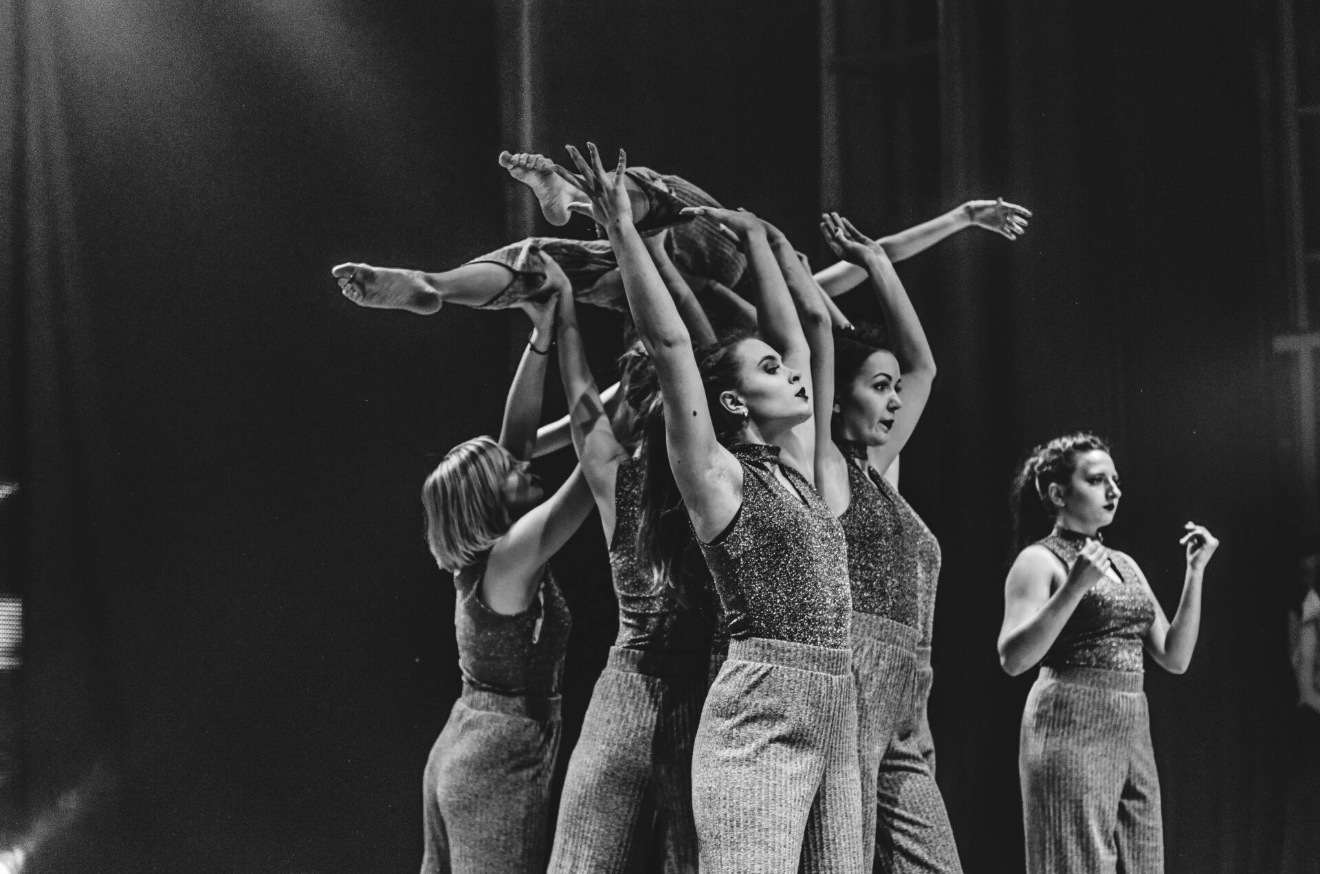 A group of women are dancing on a stage in a black and white photo.