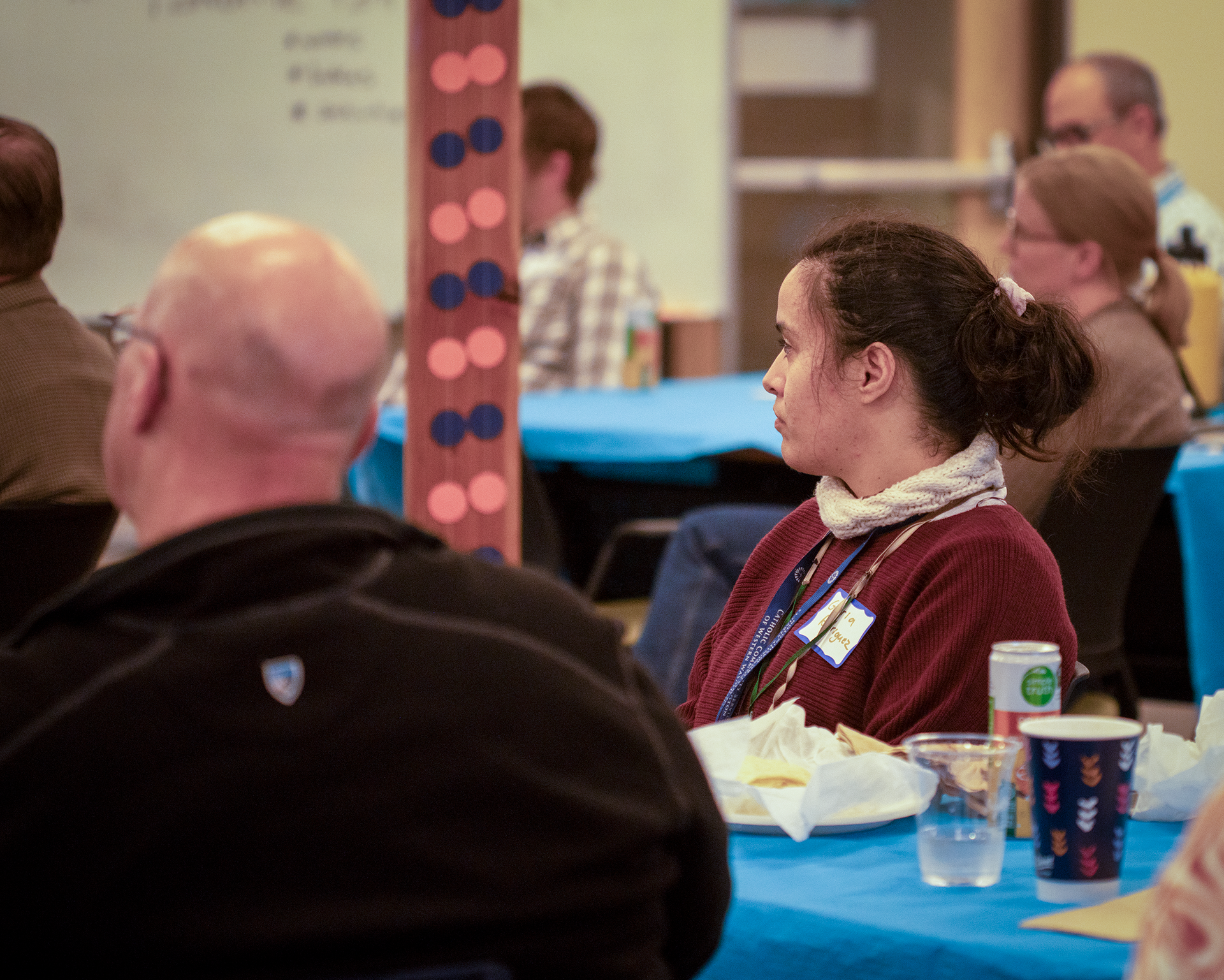 Two people watch the event at a table with decorations behind