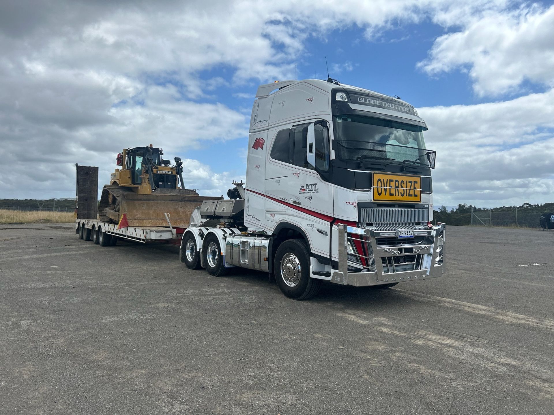 A white semi truck is carrying a bulldozer on a trailer.