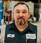 Man in mechanic uniform with name tags in a shop setting. | Emge's Car Craft Auto Services