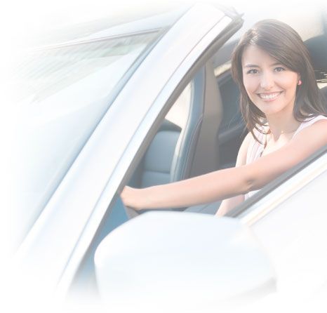 Woman smiling while sitting in a car, holding the steering wheel. | Emge's Car Craft Auto Services