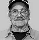 Man with glasses and mustache, wearing a hat, smiling at the camera. | Emge's Car Craft Auto Services