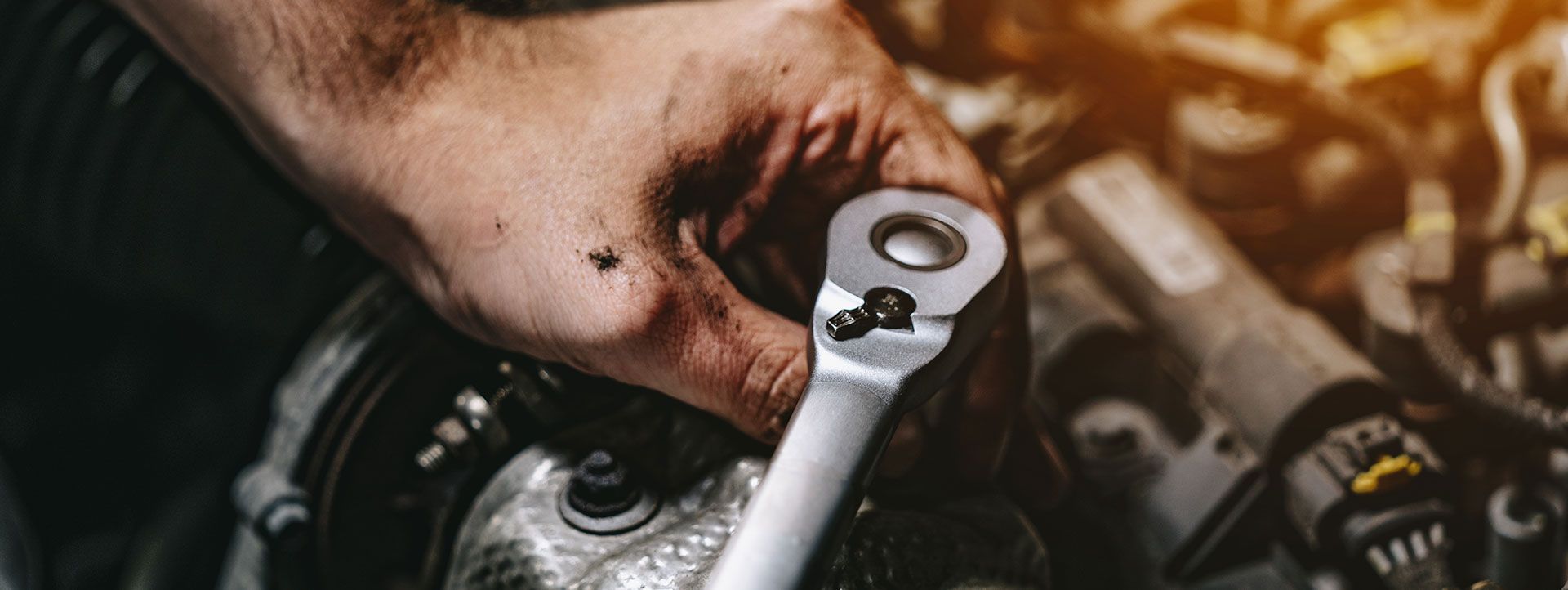 Mechanic's hand using a wrench on a car engine. | Emge's Car Craft Auto Services