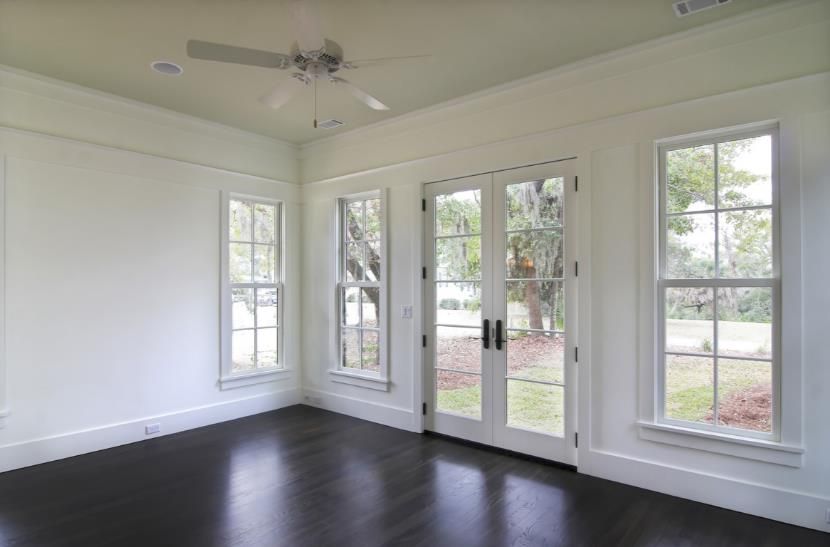 An empty room with a lot of windows and a ceiling fan.
