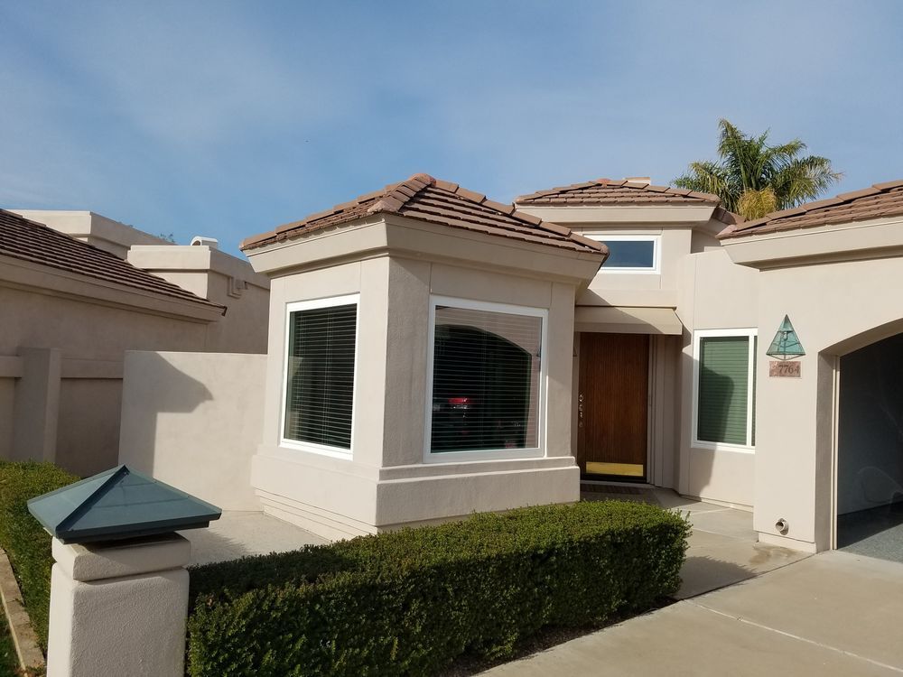 A house with a lot of windows and a hedge in front of it