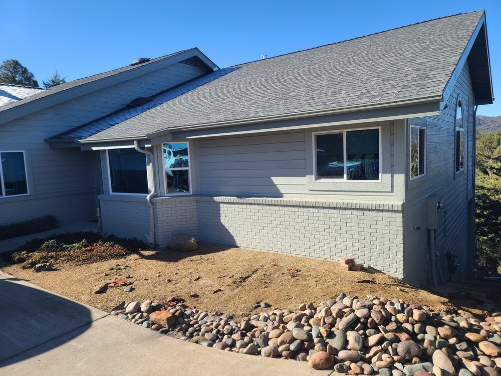 A house with a lot of windows and a lot of rocks in front of it