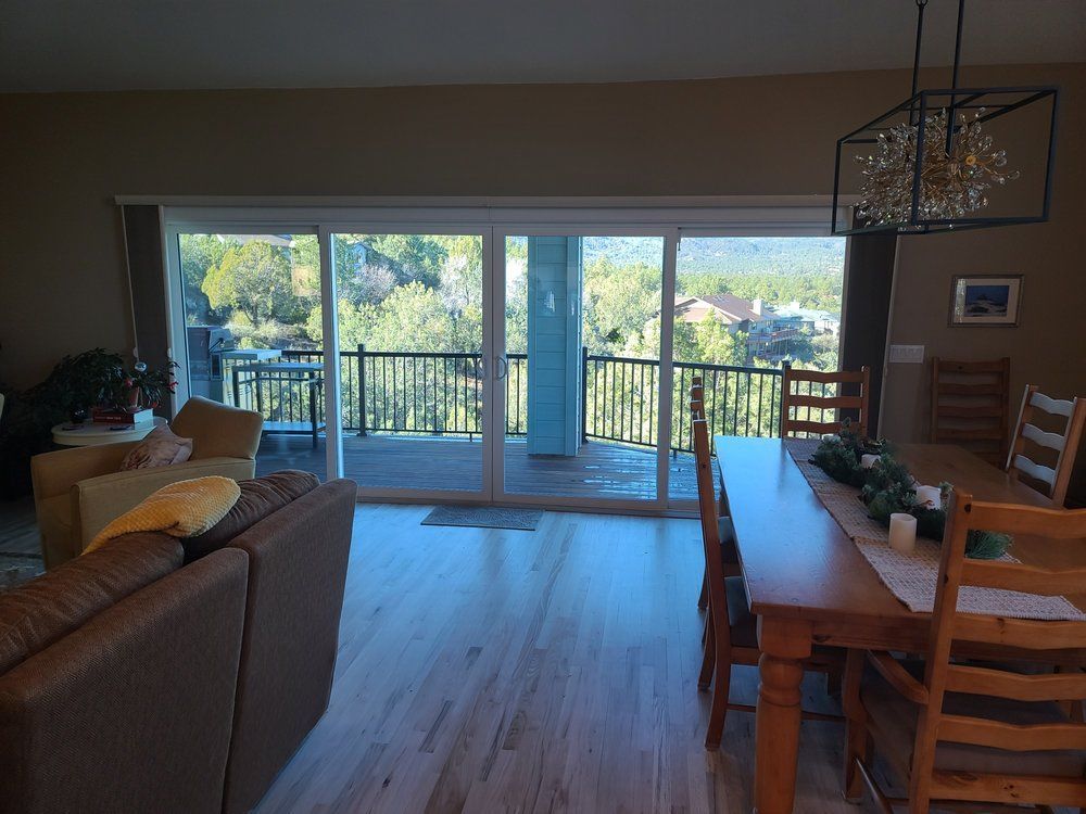 A living room with a couch , table , chairs and sliding glass doors leading to a balcony.