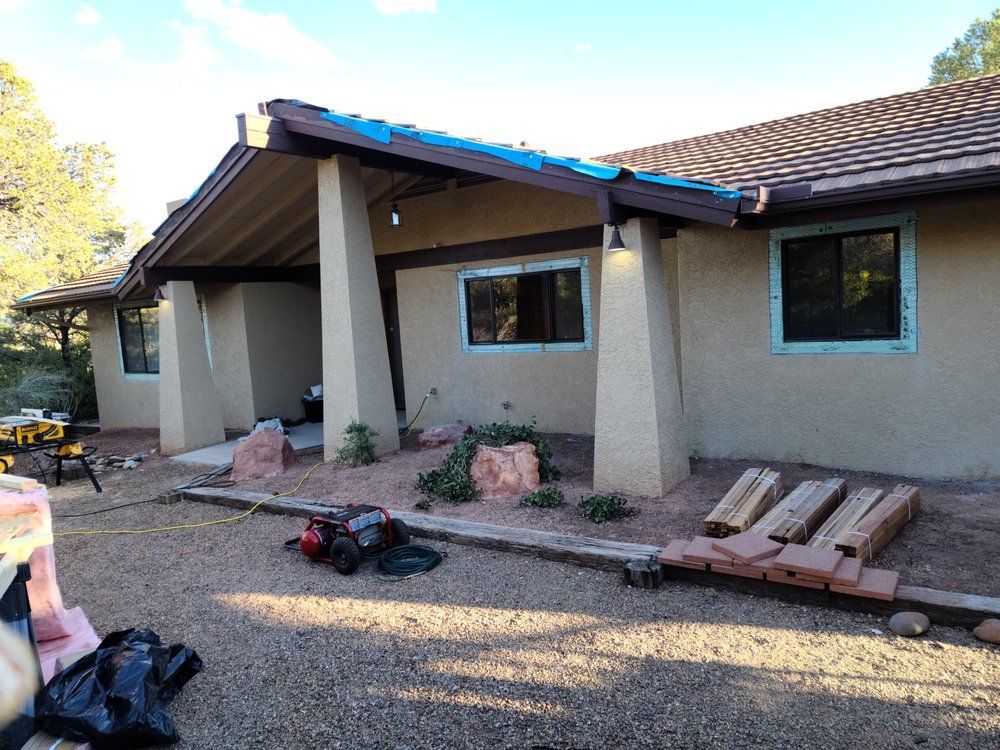 A house with a blue tarp on the roof is being remodeled
