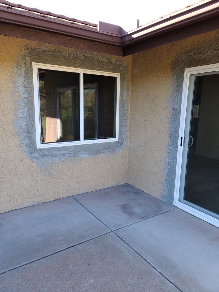 A patio with a sliding glass door and a window on the side of a house.