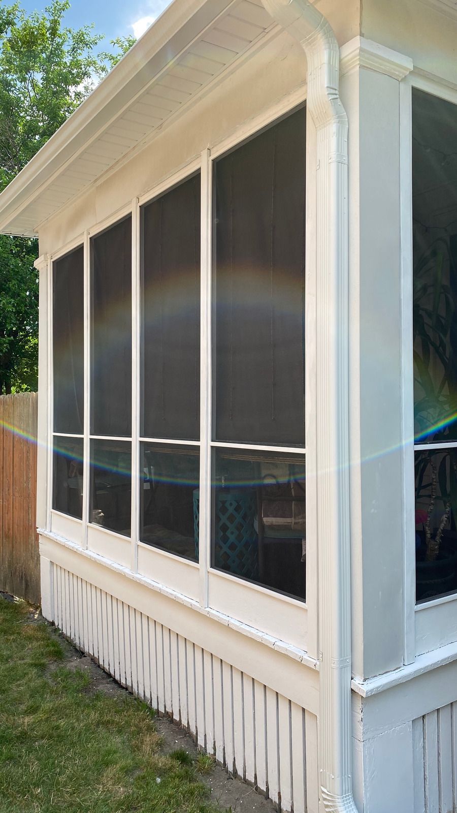 A screened in porch with a rainbow in the window.
