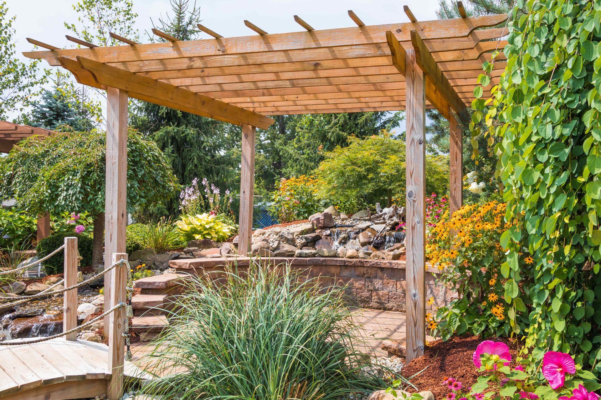 An open-air pergola sits among rocks and hardscape to create a West Coast-inspired backyard landscape.