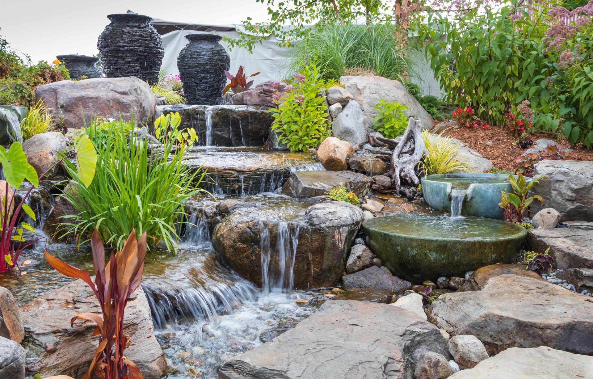 A beautiful cascading landscape waterfall surrounded by ceramic pots and basins.