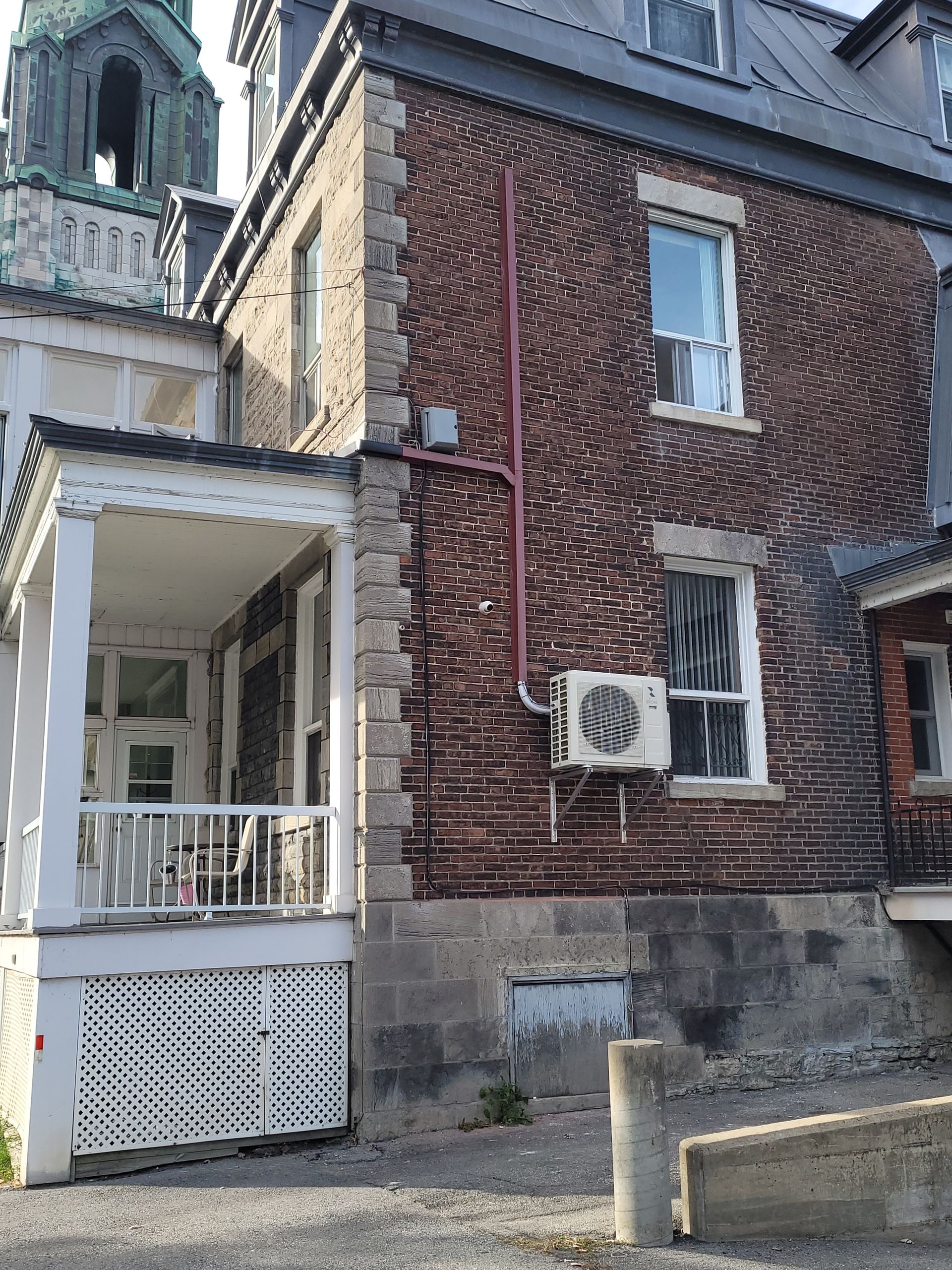 Un grand bâtiment en briques avec un porche et une tour d'horloge en arrière-plan.