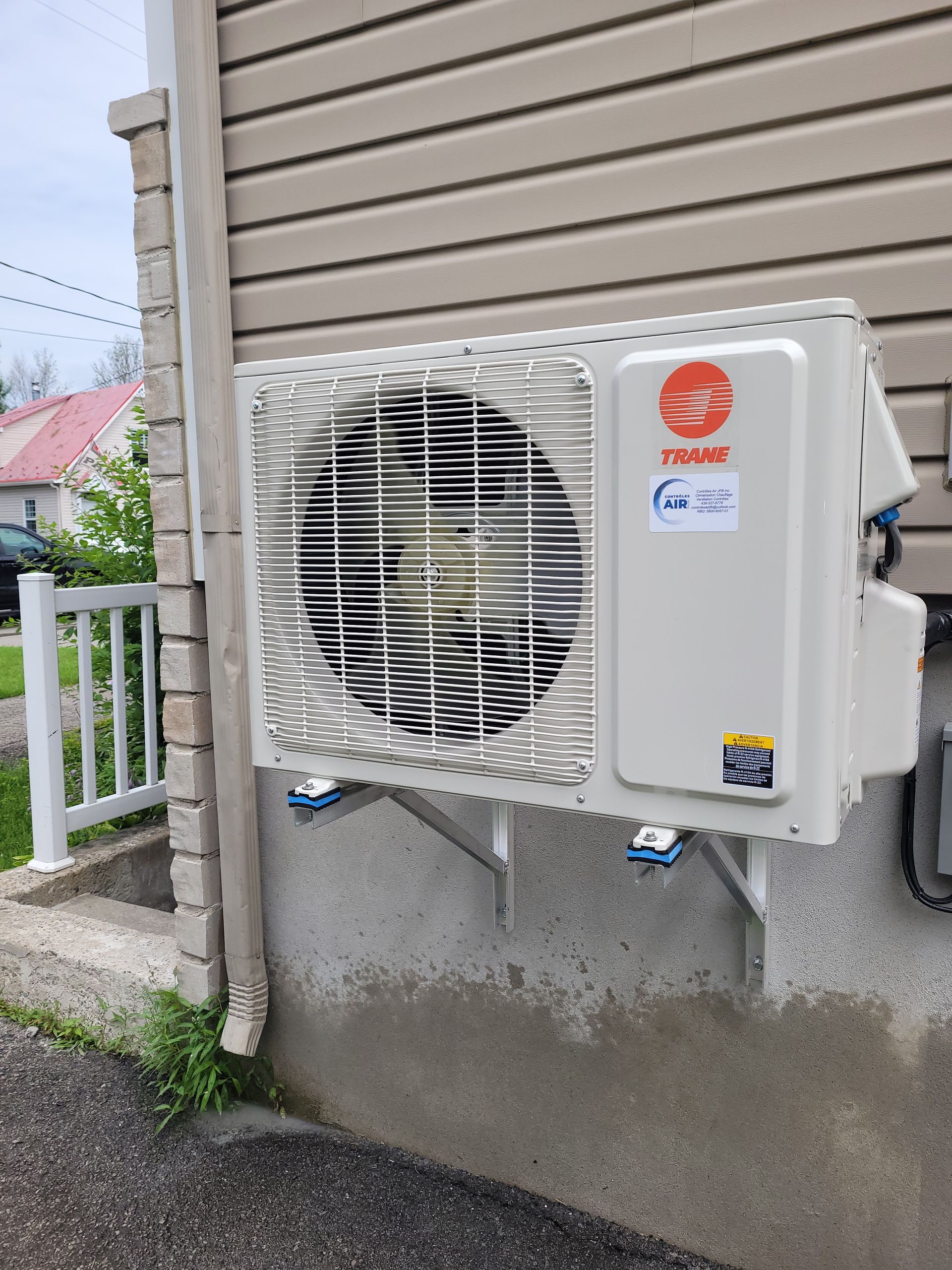 Un climatiseur blanc est monté sur le côté d'une maison.