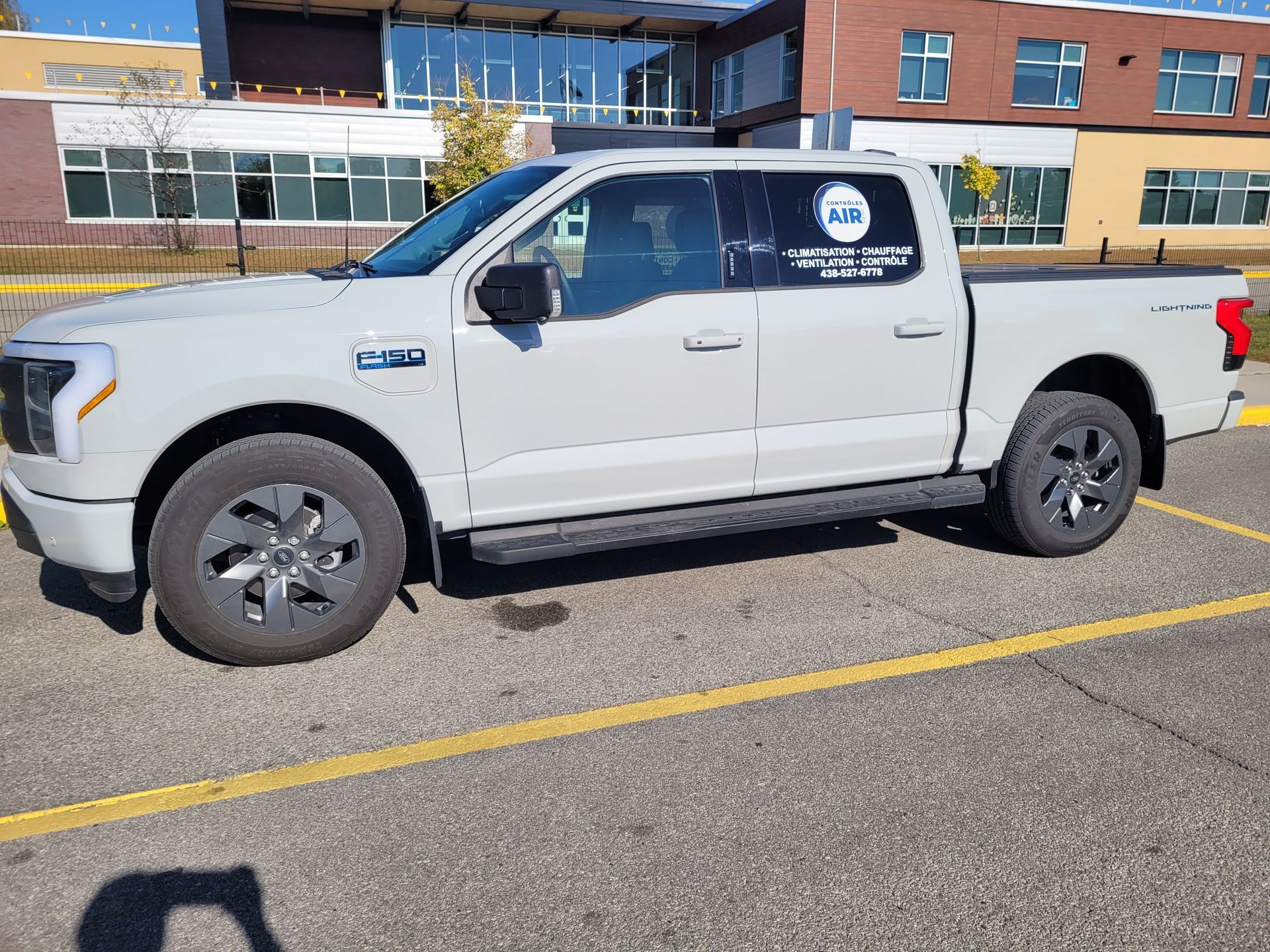 Un camion blanc est garé sur un parking devant un immeuble.