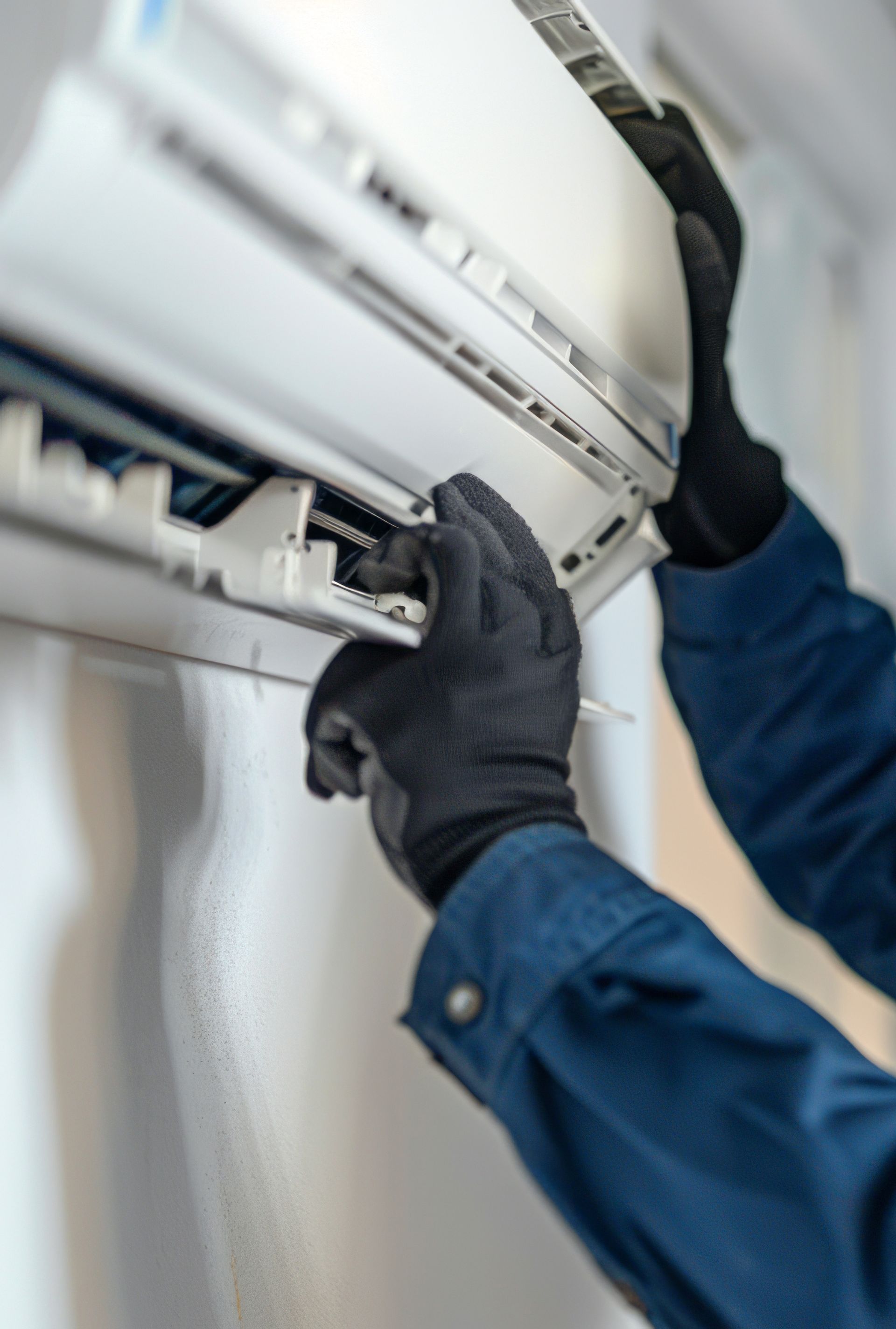 Une personne fixe un climatiseur sur un mur.