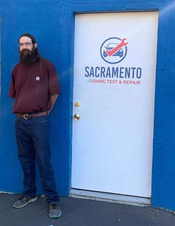 Sal standing in front of a door that says Sacramento Smog Test and Repair