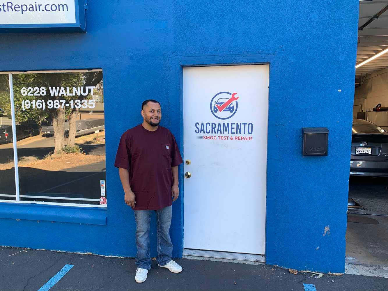 A man standing in front of a blue building  of Sacramento Smog Test and Repair