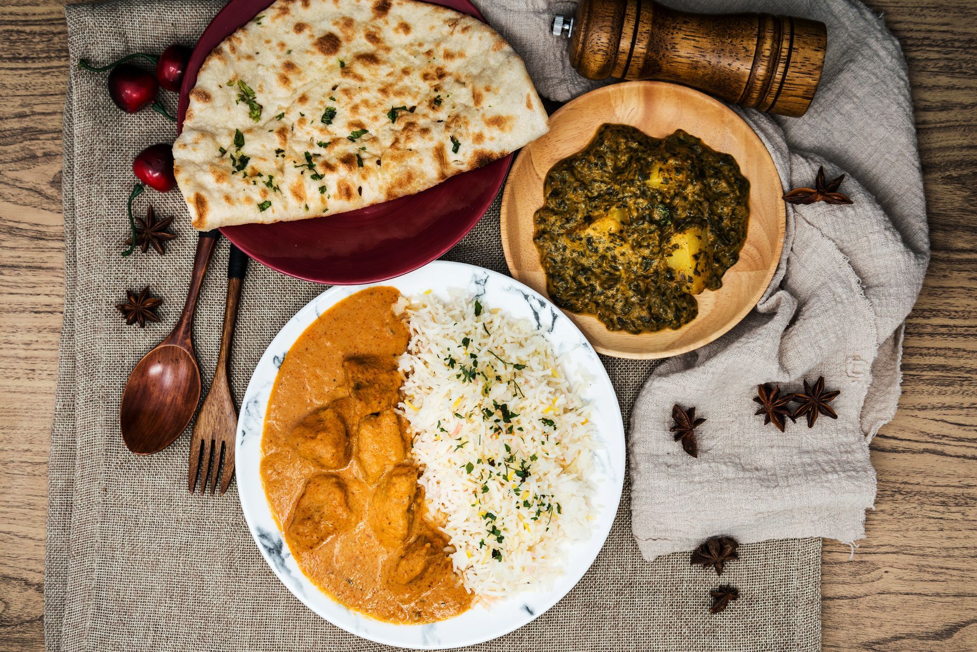 A wooden table topped with plates of food and utensils.