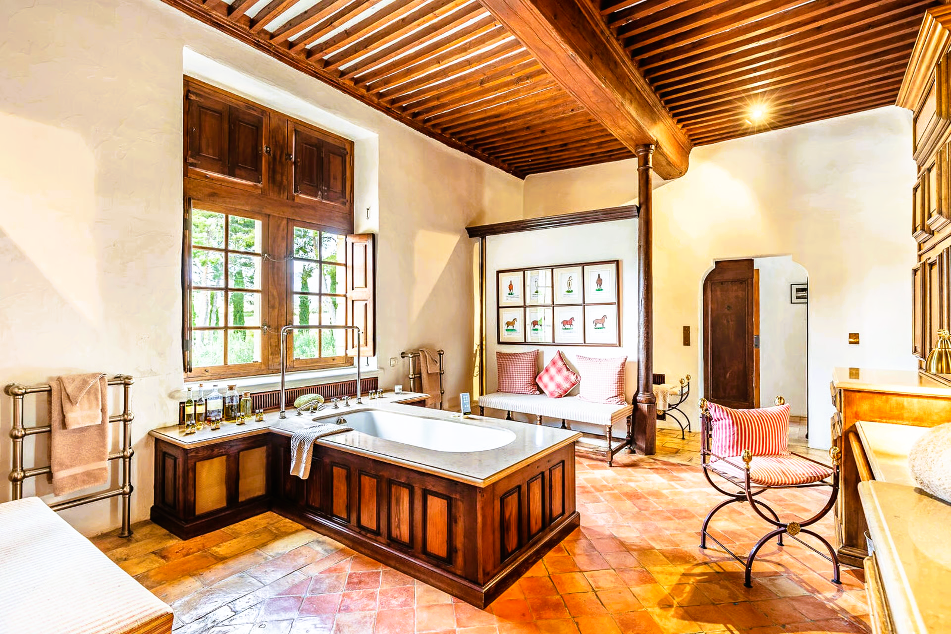 Bathroom with wood trim, tub, bench, and large window with sunlight.