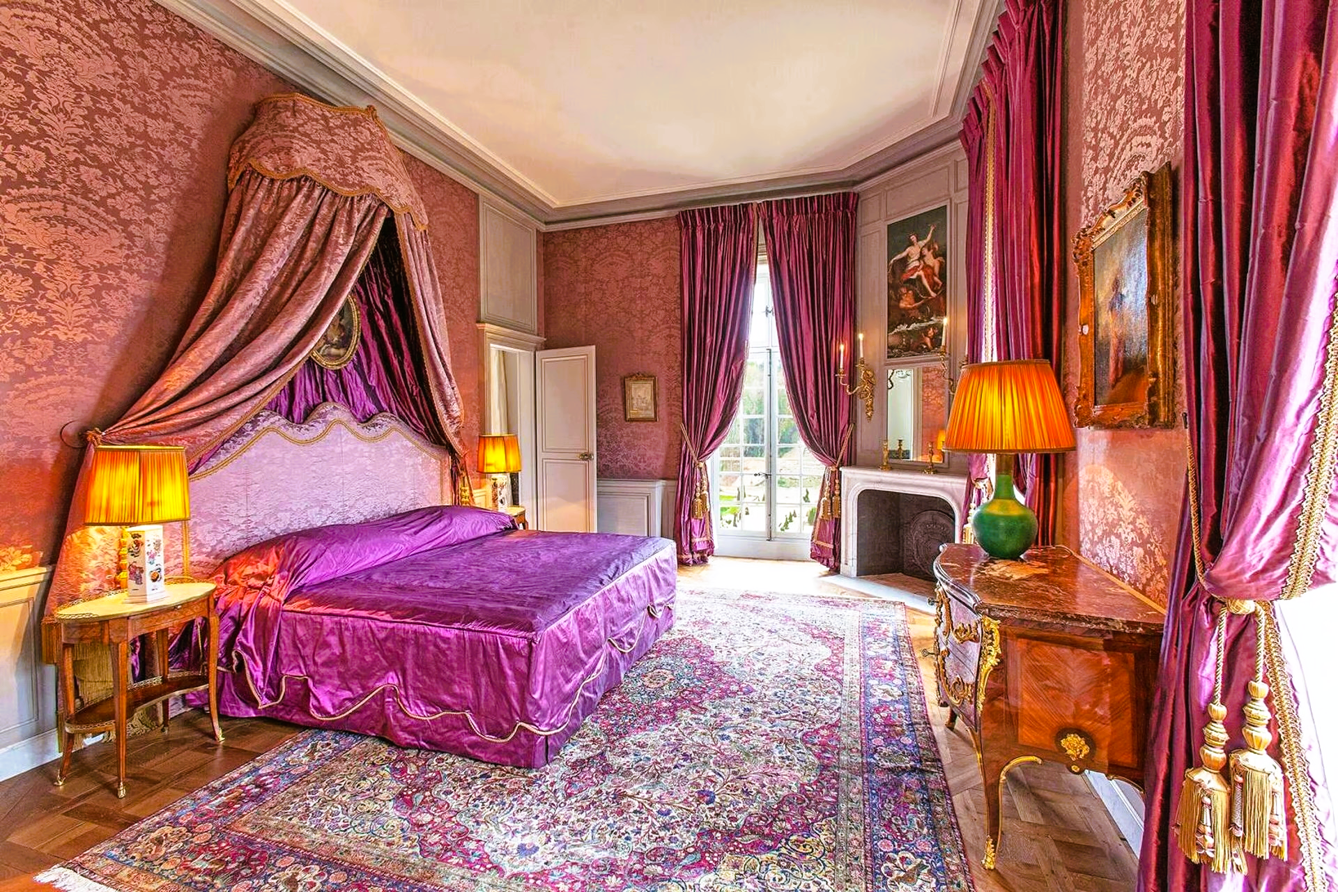 A bedroom with a purple bed and purple curtains.