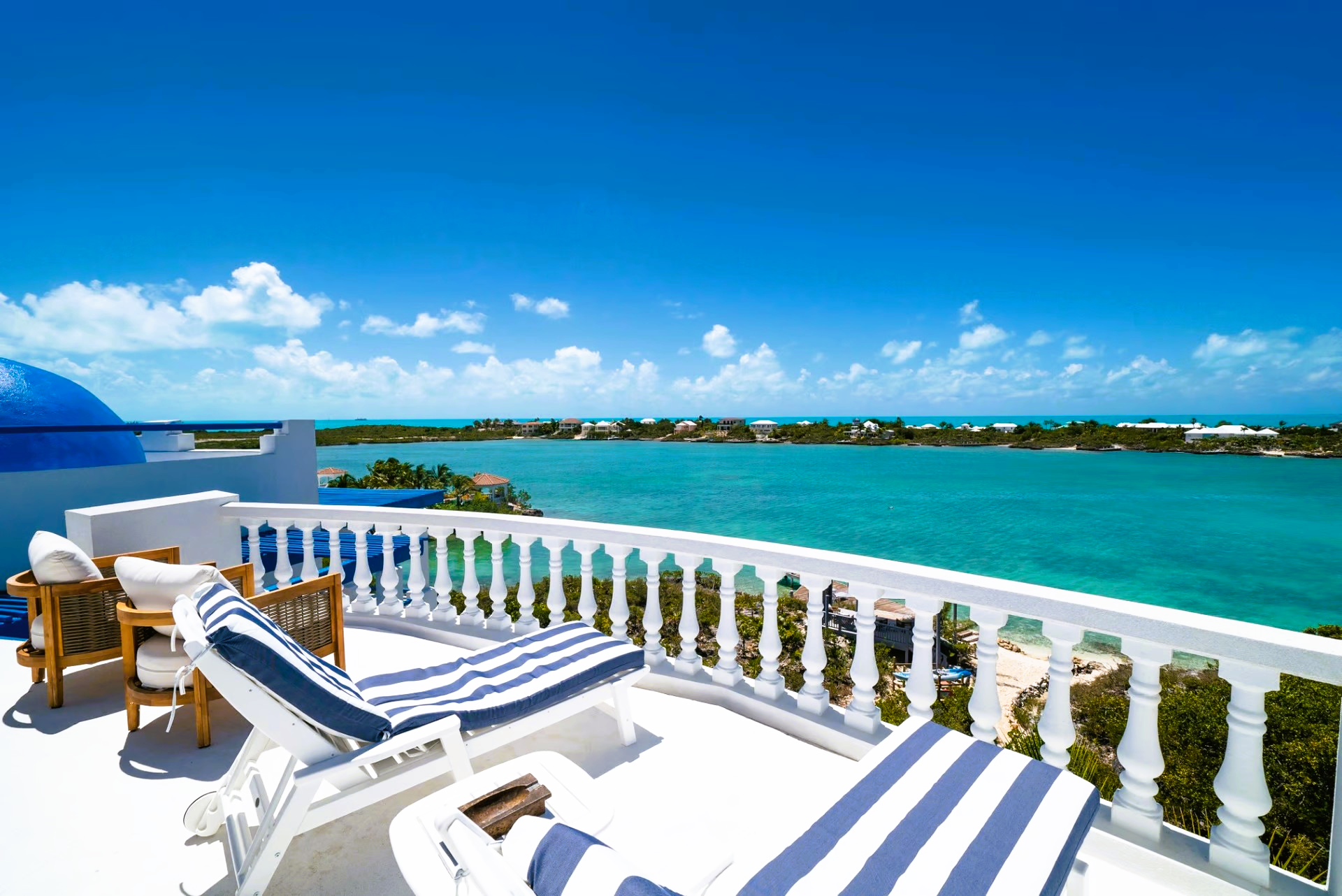 A balcony with chairs and a view of the ocean