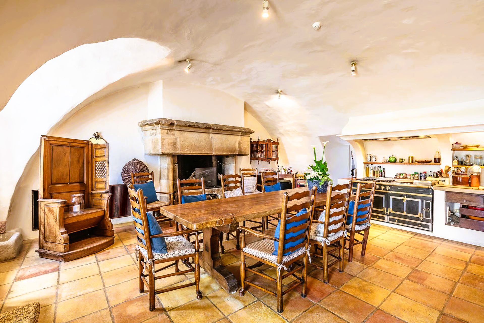 Dining room with wooden table, chairs, fireplace, and kitchen counter in a rustic setting.