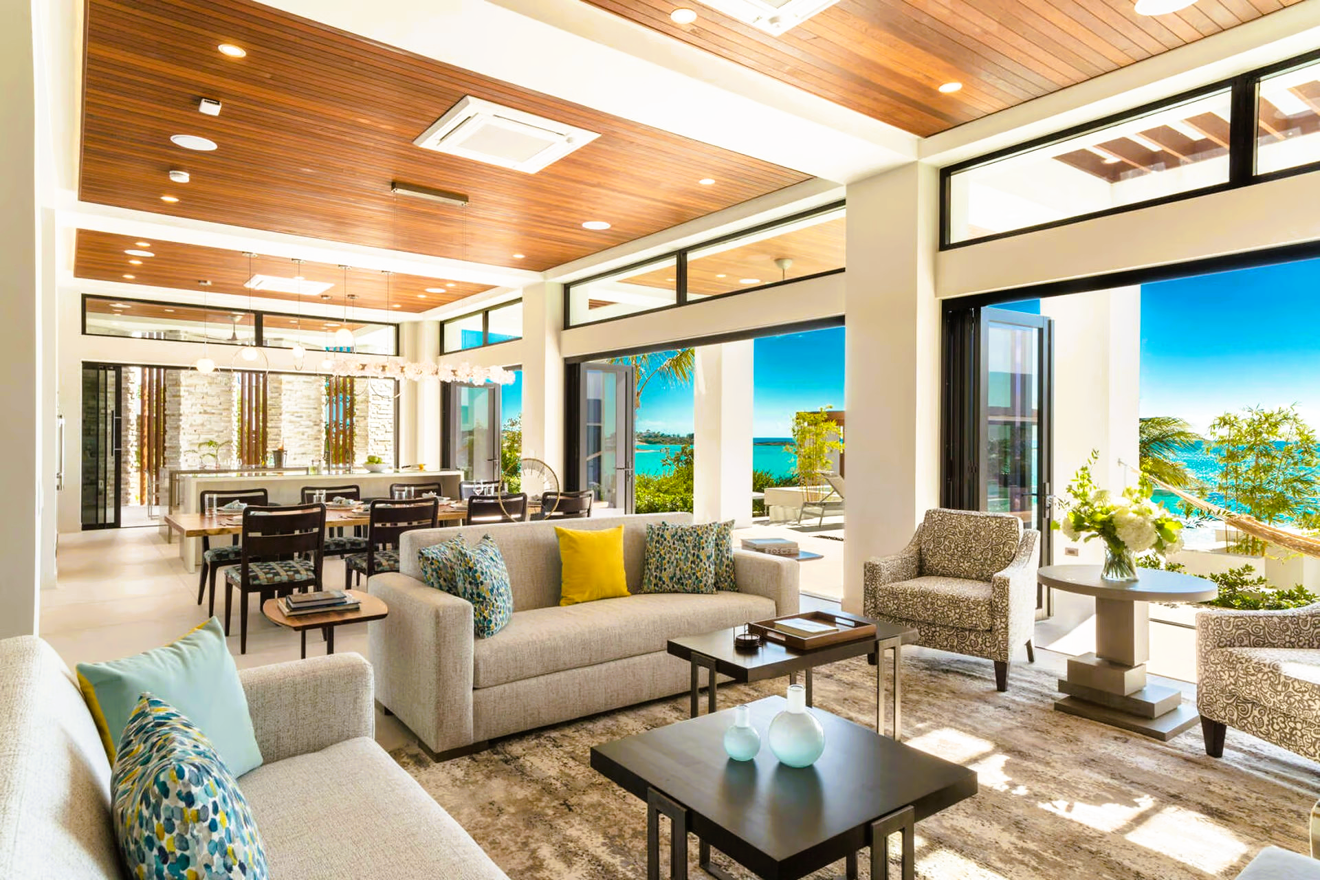 A living room with a couch , chairs , tables and a view of the ocean.