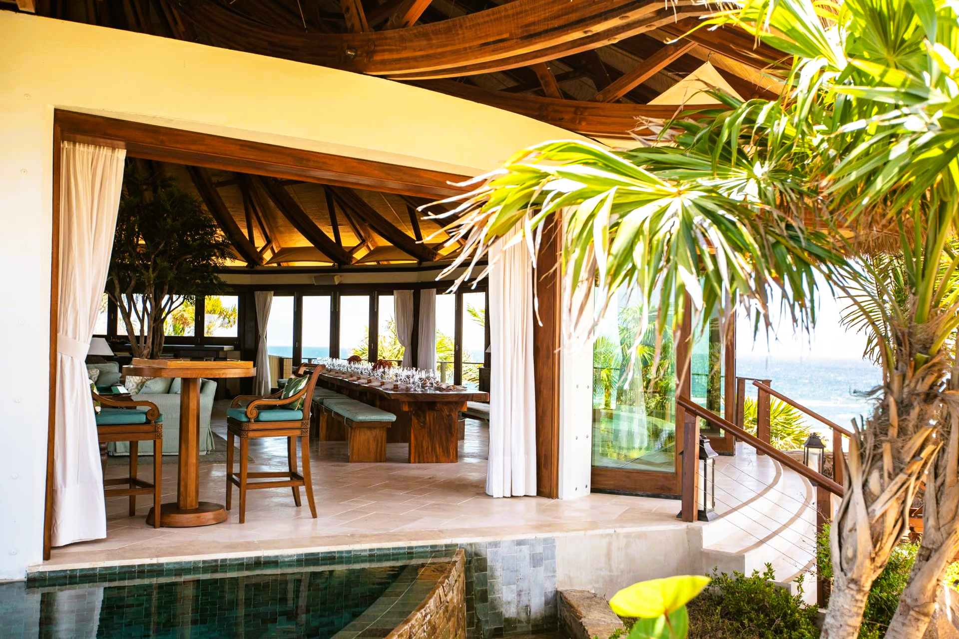 A large room with a table and chairs next to a pool.