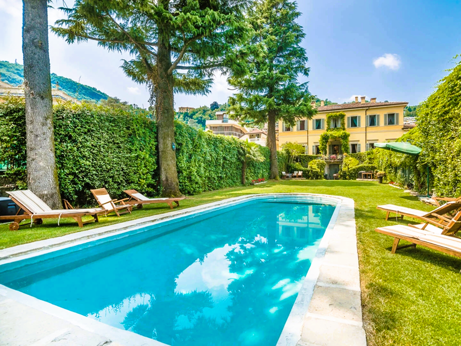 There is a large swimming pool in the backyard of a house.