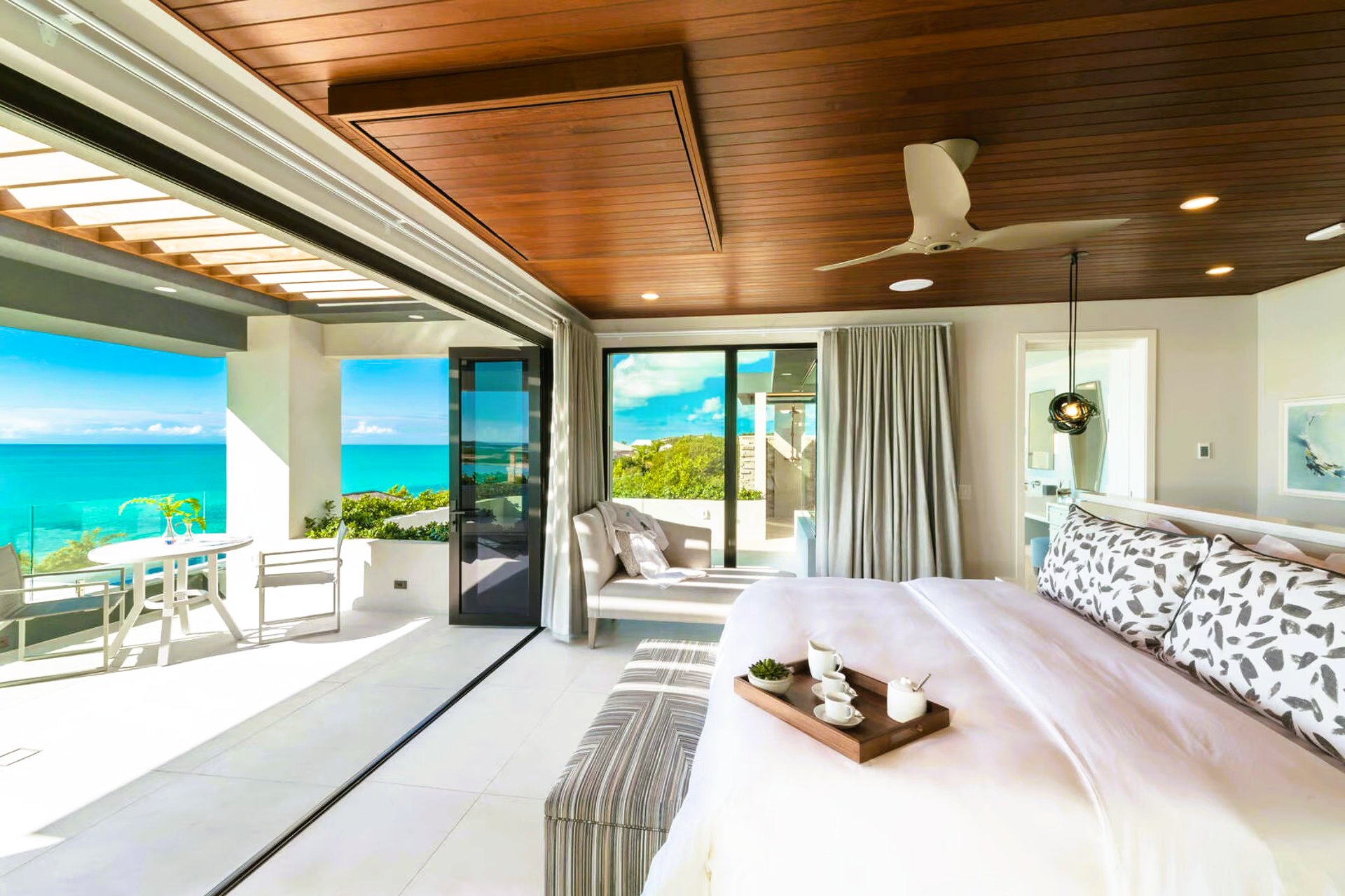 A bedroom with a large bed , a ceiling fan , and a view of the ocean.