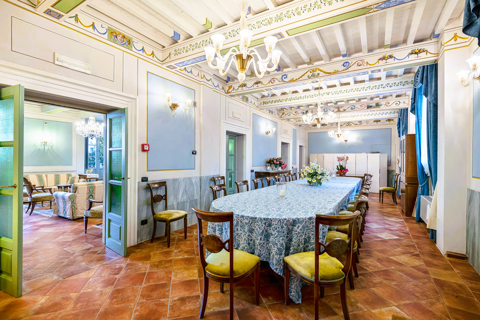 A long dining table set in a room with painted ceiling and brick floor; Italy.