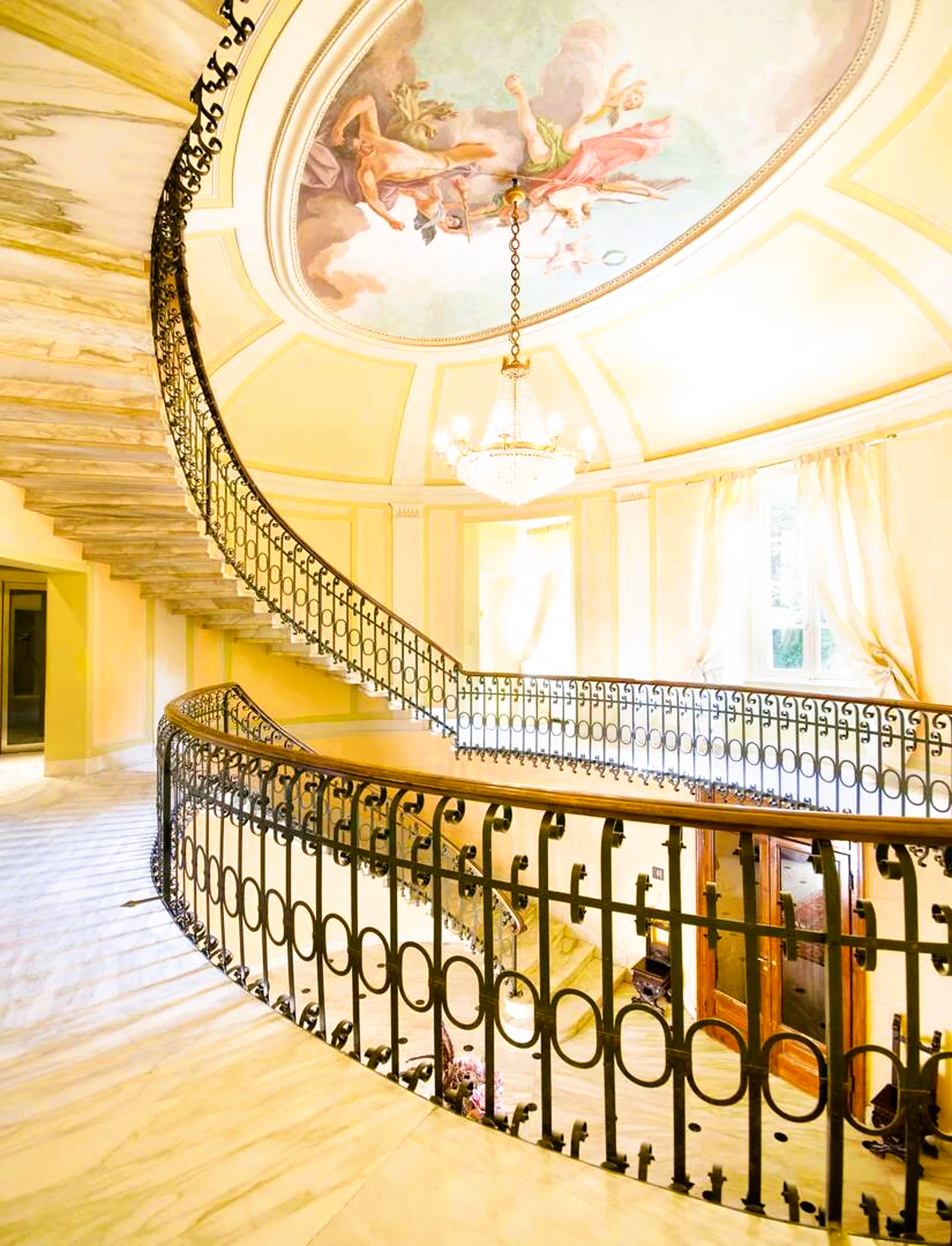 A spiral staircase with a painting on the ceiling
