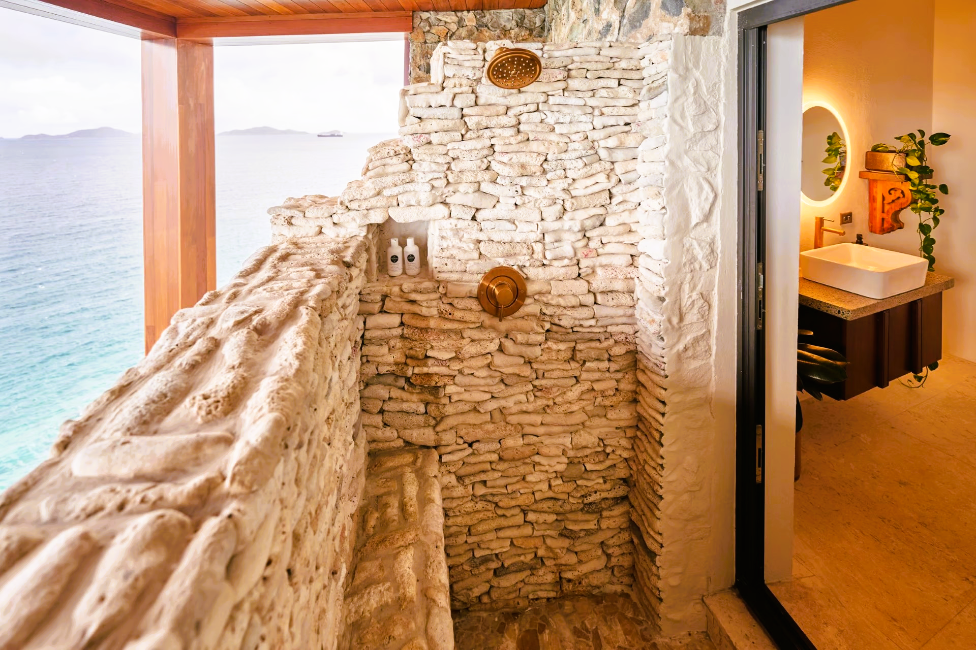 A bathroom with a stone wall and a view of the ocean.