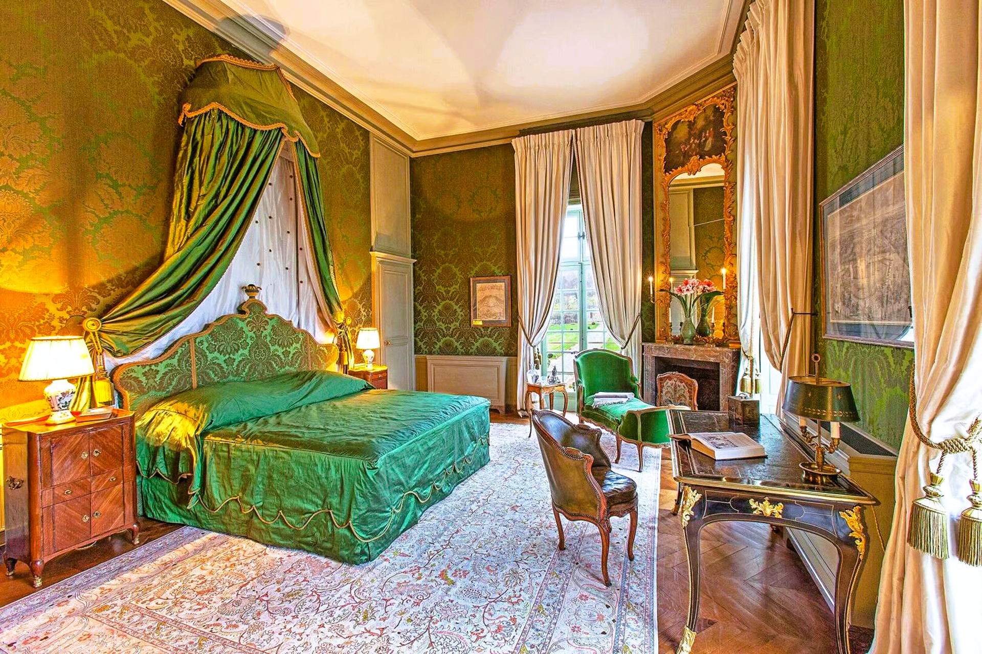 A bedroom with green walls and a green bed with a canopy.