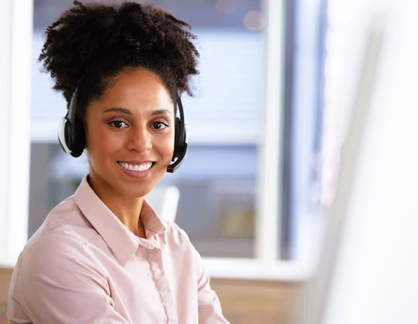Woman with headset smiling at the camera in an office setting.