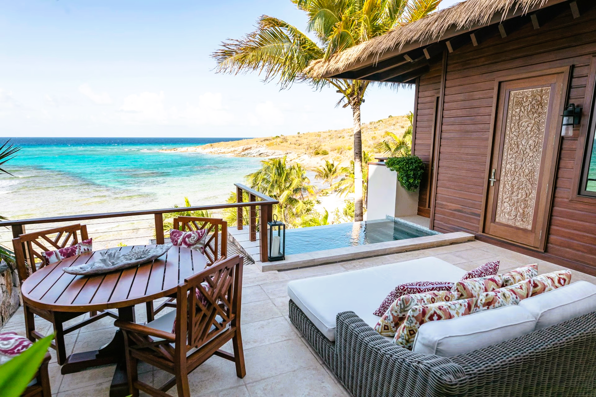 A patio with a table and chairs overlooking the ocean.